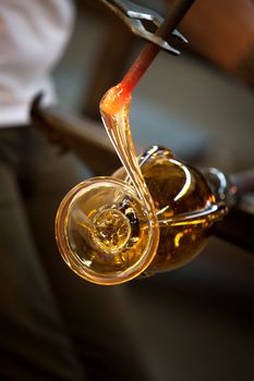 Close up of red hot molten glass with pliers 