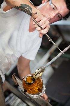 Serious young glass industrial artists forming a vase
