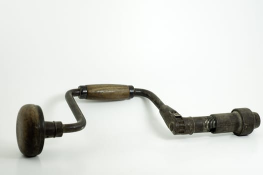 antique hand drill with wooden handles and crank on white background