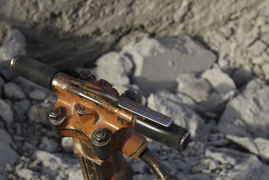 jack hammer handle used for breaking, chipping, and demolishing concrete with crushed concrete in background