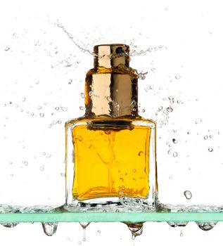 Small rectangular bottle of perfume all in a spray of water on a white background