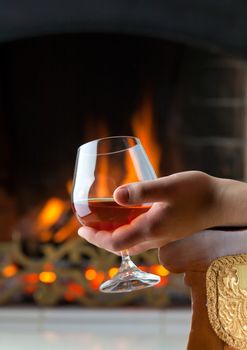 A glass of cognac on the background of a burning fireplace