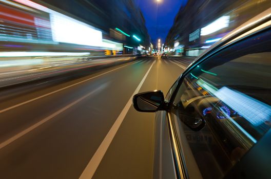 Cars driving through the city with such speed that the lights of the city reserves the long tracks