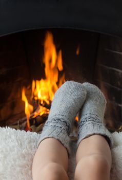 Children's feet in warm woolen socks heated in the fire in the fireplace