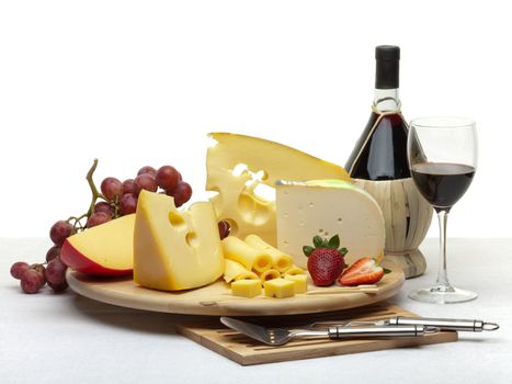 Composition of cheese, grapes, bottles and glasses of wine and strawberries on a wooden round tray on a white tablecloth, isolated on a white background