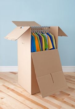 Wardrobe box filled with colorful clothing, prepared for transportation.