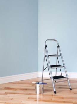 Metal ladder and a can of paint in empty room. Renovation project.