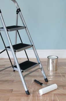 Room prepared for painting. Ladder, painting tools and floor protected by plastic. 