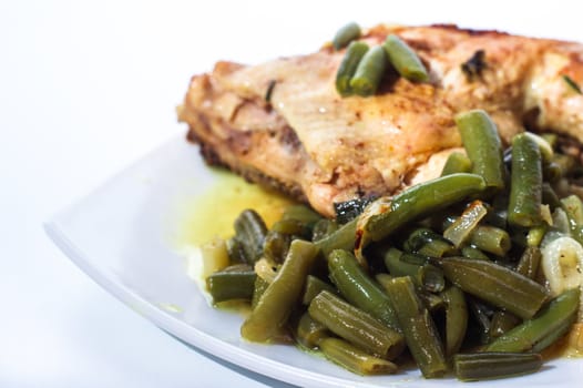 Fried chicken leg with french beans on white plate. Isolated.