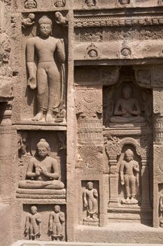 Religious figures carved out of the rock on the facade of an ancient Buddhist cave temple Ajanta Caves near Aurangabad India. 5th-6th Century AD