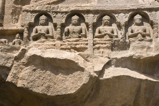 Religious figures carved out of the rock on the facade of an ancient Buddhist rock temple (cave 26), Ajanta Caves near Aurangabad, India. 5th-6th Century AD.