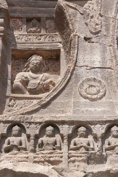 Religious figures carved out of the rock on the facade of an ancient Buddhist rock temple (cave 26), Ajanta Caves near Aurangabad, India. 5th-6th Century AD.