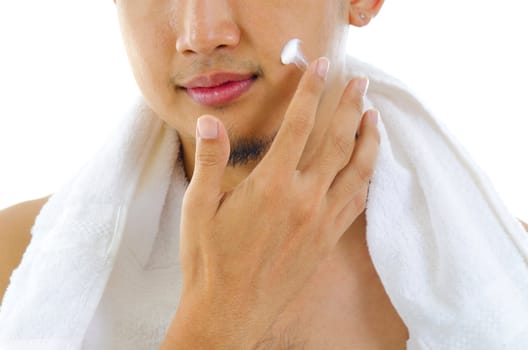 Asian man putting on cream lotion on face