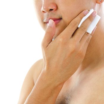 Asian man cleaning face with facial cotton, isolated on white background