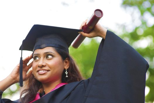 Young Asian Indian female student adjusting her graduate hat