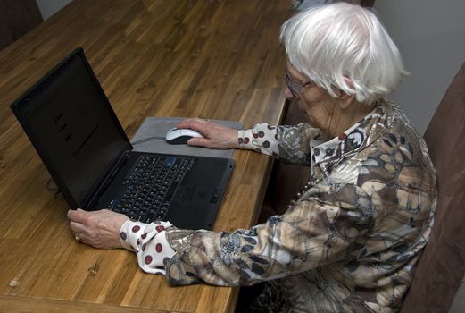 older senior woman above eighty years old working with a laptop computer
