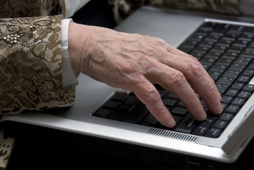 hand of a woman older then 80 , working on a mobile laptop