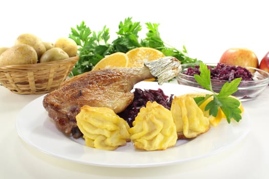 fried Duck drumstick with duchess potatoes and red cabbage on a light background