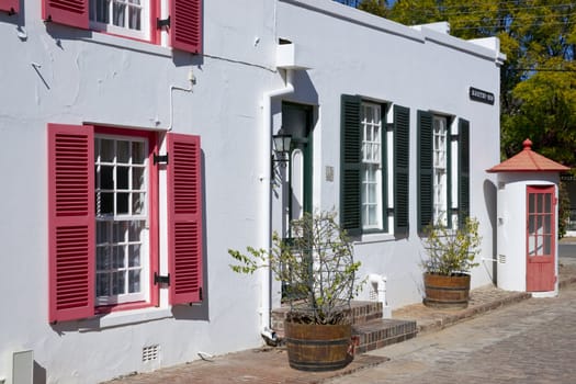 Historic architecture in Graaff-Reinet, Eastern Cape, South Africa. White building in Cape Dutch style with colorfully painted window frames.