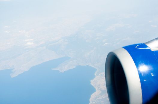 airplane wing, turbine, sky and clouds as seen through the cabin window