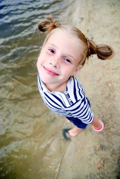 Little girl on the beach looking at the camera from the bottom up