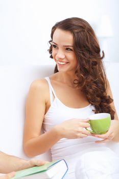 Young pretty woman in white at home sitting on the sofa