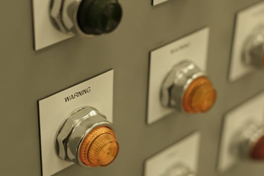 bright orange warning light on electrical panel shallow depth of field