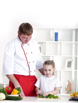 portrait of father and daughter cooking salad together in the kitchen