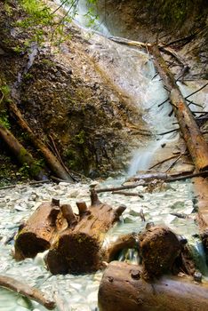 One of the many crystal clear waterfalls in the Slovakian paradise natural park with wooden logs in the front