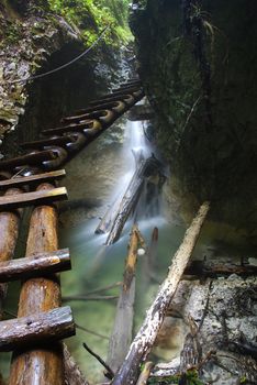 Extreme Adventure in Slovakian National Park Slovensky Raj. Climbing on slippery ledders over wild brook with waterfalls in Sokolia roklina canyon