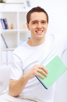 Young handsome man at home with a book