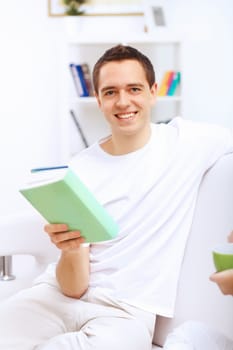 Young handsome man at home with a book