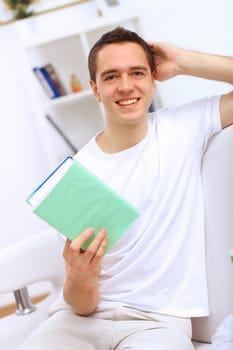 Young handsome man at home with a book