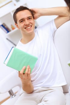 Young handsome man at home with a book