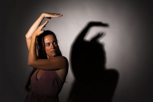 Dancer in a strong, expressive attitude with shadow on wall