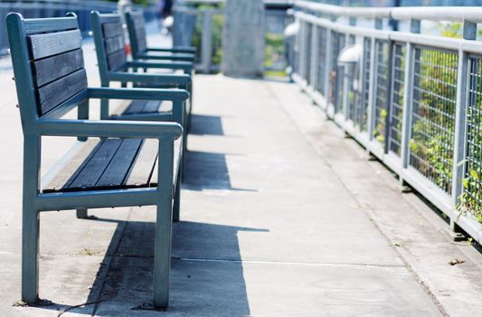 Green wood and metal Benches with closest in focus trailing to softer background