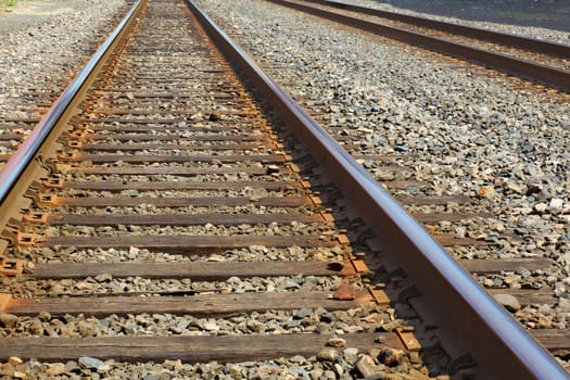 Two sets of Diminishing straight train tracks on a gravel bed