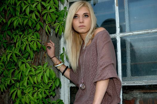 Young female model wears casual clothes. Teenage girl cool and relaxed standing near the window.