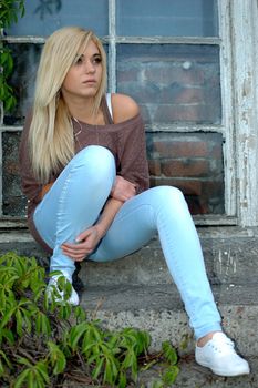 Young female model wears casual clothes. Sits on stairs with natural face expression, teenage girl cool and relaxed.