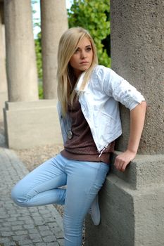 Young female model wears casual clothes. Standing near column with natural face expression, teenage girl cool and relaxed.