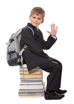 Schoolboy sitting on books isolated on a white background