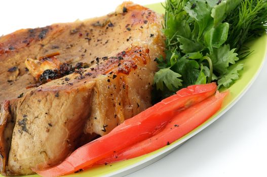 Pork Chop with Tomatoes and Greens close up on Green Plate isolated on white background