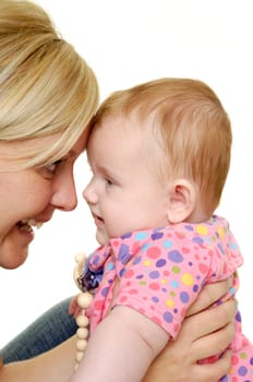 Mother is looking down on her sweet smiling baby. Taken on a white background.