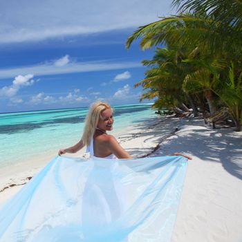 woman with a white fabric in his hands on the beach