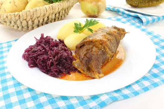 stuffed Beef roulade with potatoes and red cabbage on a light background