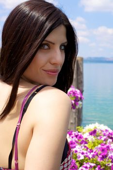 Smiling gorgeous female model looking on a lake with pink flowers