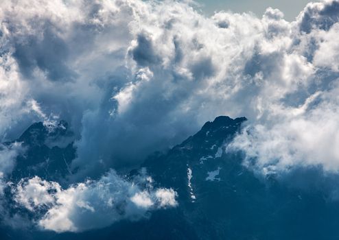 Image of impressive clouds gathering over the high mountain peaks in The Alps.