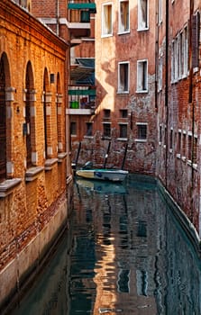 Image of a narrow Venetian Canal between old buildings.