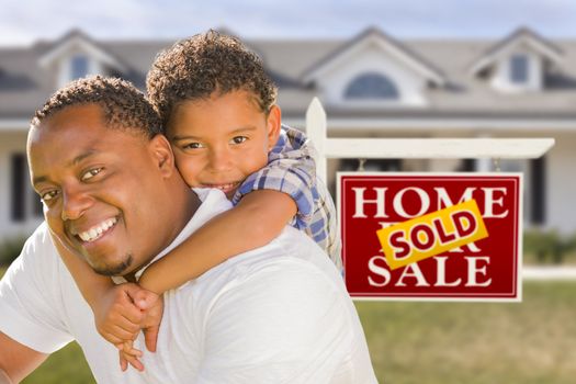 Happy Mixed Race Father and Son In Front of Sold Real Estate Sign and New House.