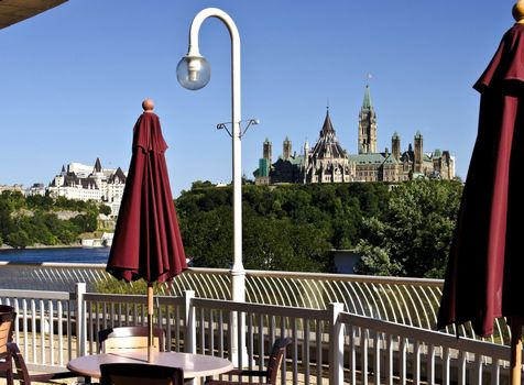 The canadian Parliament Centre block and Library seen from a patio across the Ottawa river.